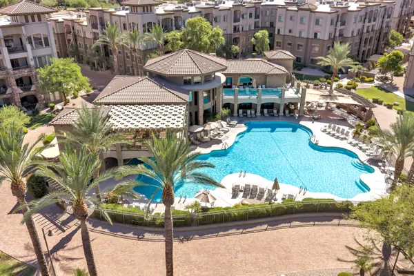 Aerial real estate photography of a luxury apartment complex with a large swimming pool in Phoenix, AZ, showcasing resort-style amenities and lush landscaping.