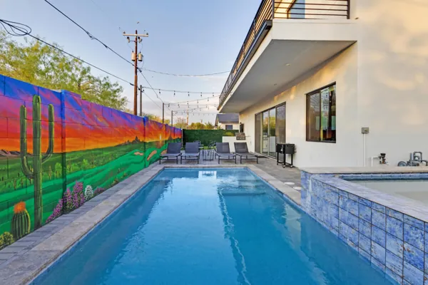 This Scottsdale, AZ property features a vibrant mural by the pool with modern lounge seating, captured with professional real estate photography showcasing an inviting outdoor living space perfect for relaxation.
