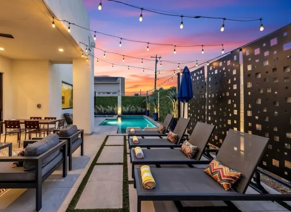 Beautiful twilight real estate photography showing a modern poolside patio with lounge chairs and string lights in Scottsdale, AZ.