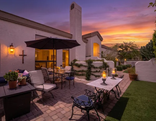 Beautifully staged backyard patio at sunset in Scottsdale, AZ, showcasing inviting outdoor seating and warm lighting, captured in professional real estate photography.